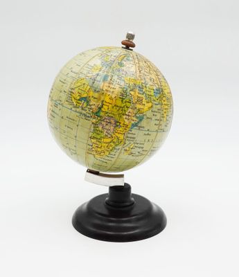 un petit globe posé sur un socle, sur une surface blanche