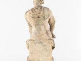 a statue of a woman sitting on a block with her back to the camera