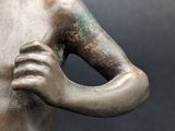 a bronze statue of a woman with her hands on her chest