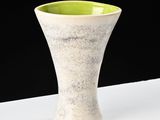 a white and green vase sitting on a white table
