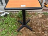 une petite table en bois posée à même le sol, avec un piètement noir