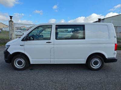 the white van is parked in the parking lot near a fence