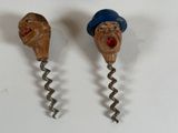 two cork openers with faces on them on a white surface
