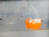 une photo d'un seau orange posé contre le mur d'un immeuble