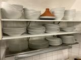 many plates and bowls stacked on the shelves in the kitchen