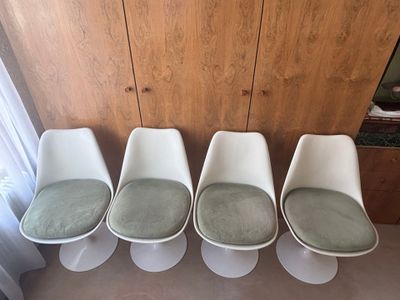 quatre chaises blanches alignées les unes à côté des autres devant un mur en bois