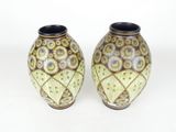 two vases that are sitting side by side on a white surface