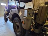 a military jeep parked in a garage with its hood up