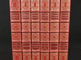 six red books are lined up in a row on a black surface