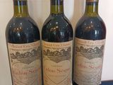 three bottles of red wine sit on a blue surface