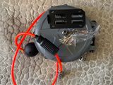 un aspirateur posé par terre, avec un cordon rouge