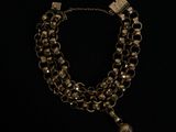un collier composé d'une chaîne à laquelle est suspendue une clochette