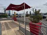 un parapluie rouge au-dessus d'une jardinière rouge au bord de la route