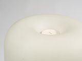 a white candle that is lit on a white table