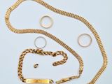 un bracelet en chaîne d'or, une bague et un ensemble de bagues posés sur un fond blanc