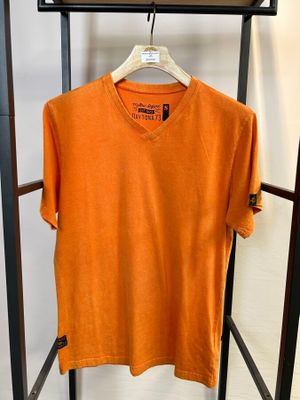 un t-shirt orange suspendu à un portant dans une pièce