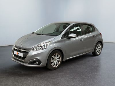La voiture argentée est garée dans une grande pièce au sol noir.