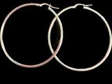 une paire de boucles d'oreilles créoles en argent sur fond noir