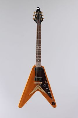 une guitare électrique orange suspendue à une ficelle sur un mur blanc