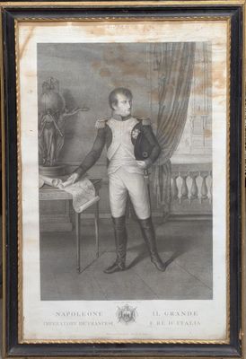 une vieille photo montrant un jeune garçon en costume, debout devant une table