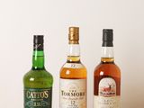 trois bouteilles d'alcools différents posées sur une table en bois