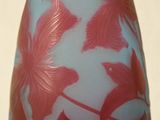 un vase bleu orné de fleurs rouges, posé sur un fond blanc
