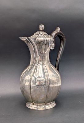 an old silver pitcher with a handle on a gray background