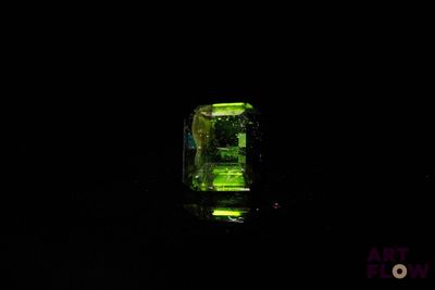 an emerald stone lit up in the dark on a black background