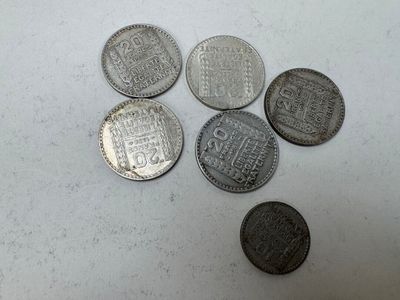 six types différents de pièces d'argent sur une surface blanche