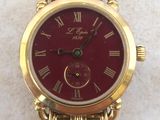 a gold watch with a red face on a white surface
