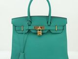 un sac à main en cuir vert muni d'un fermoir doré sur la poignée
