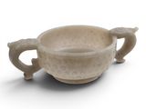 une petite tasse avec une anse posée sur une surface blanche