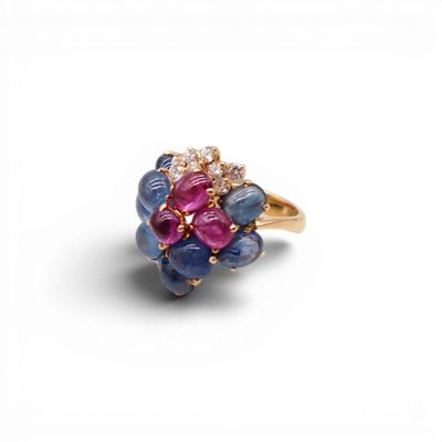 un gros plan d'une bague en or sertie de pierres bleues, roses et blanches