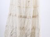 a white skirt hanging on a black hanger against a white wall