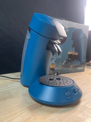une cafetière bleue posée sur une table à côté d'une boîte de café