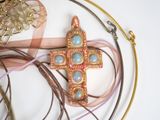 a gold cross on a pink ribbon and some other jewelry