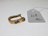 une petite bague en or et une étiquette sur une surface blanche