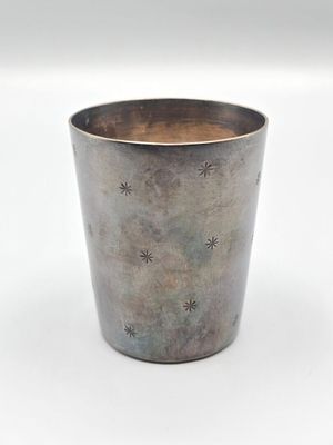 une coupe en argent ornée d'étoiles, posée sur une surface blanche