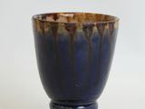 a blue and brown cup sitting on a white surface