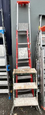 several ladders are lined up against a wall in front of a building