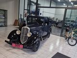 a vintage car in a showroom with bicycles in the background