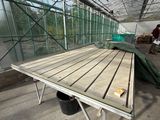 a wooden table in the middle of a large greenhouse