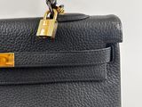 a black leather handbag with a gold lock on the handle