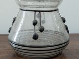 a glass jar with a handle sitting on a wooden table