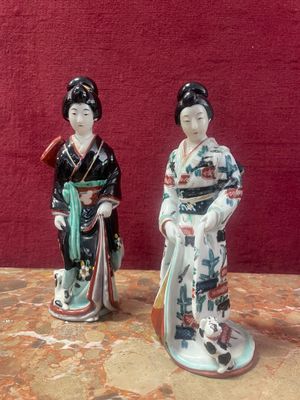two figurines of asian women standing next to each other