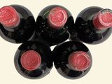 six bottles of wine are arranged in a row on a white surface