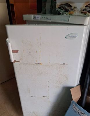 un réfrigérateur blanc posé dans le coin d'une pièce