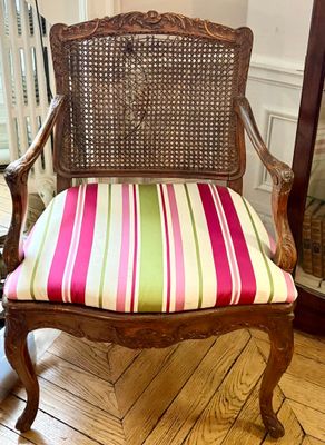 une chaise en bois avec une assise rayée et un miroir en arrière-plan