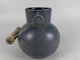 a blue vase with a wooden handle on a white table