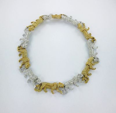 un gros plan d'un collier en or et en argent posé sur une surface blanche